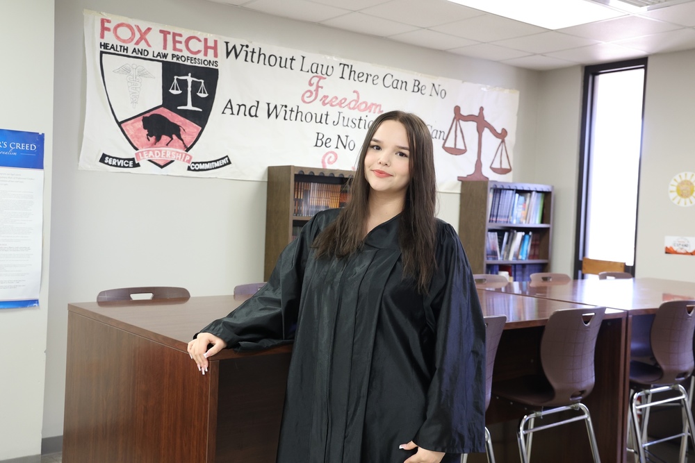 Student judge wears robe in front of Fox Tech Banner