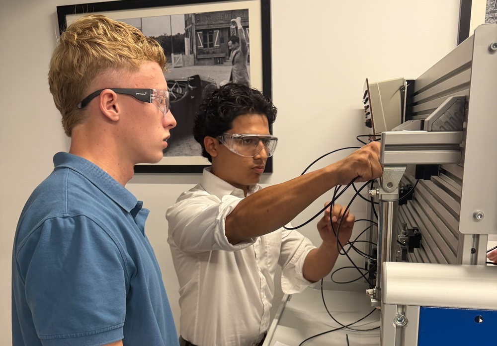 Two male students with safety goggles connecting wires