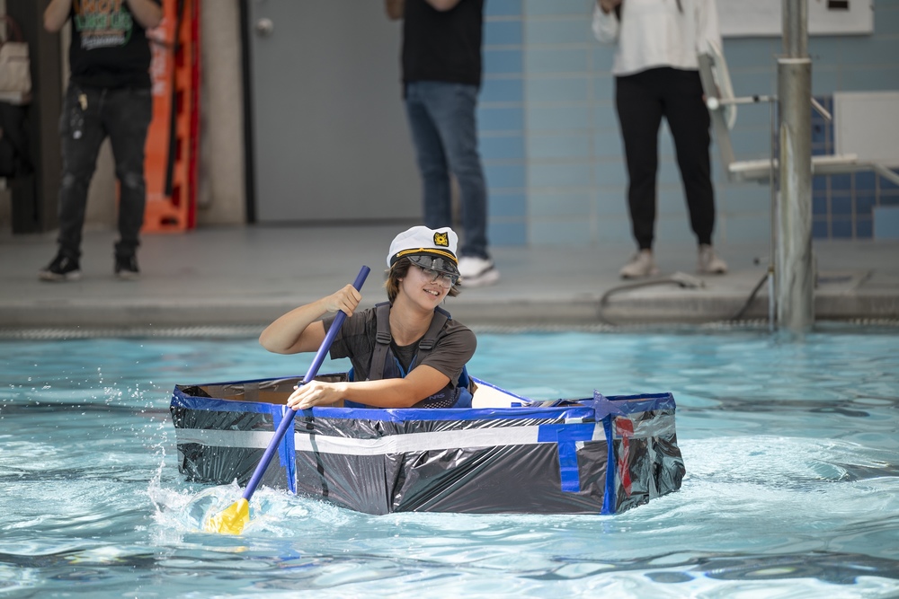 Girl rows boat made of trash bags cardboard and duct tape