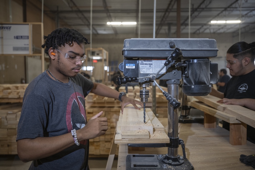 Male student with safety goggles uses drill