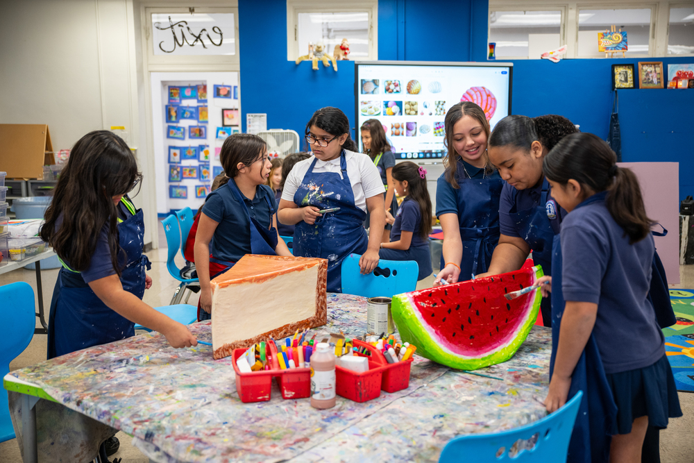 Girls paint large papier mache cheesecake and watermelon