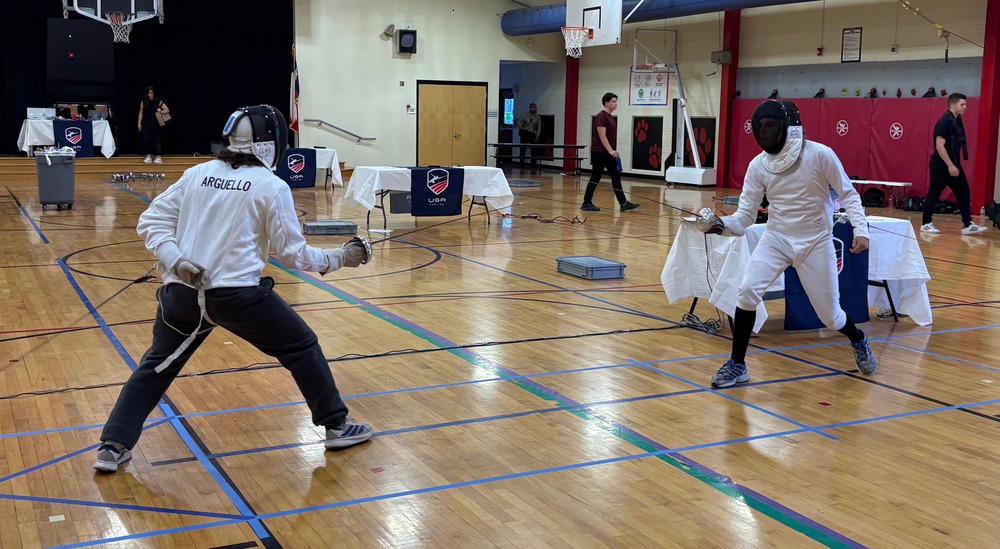 Two students in protective gear hold epee swords