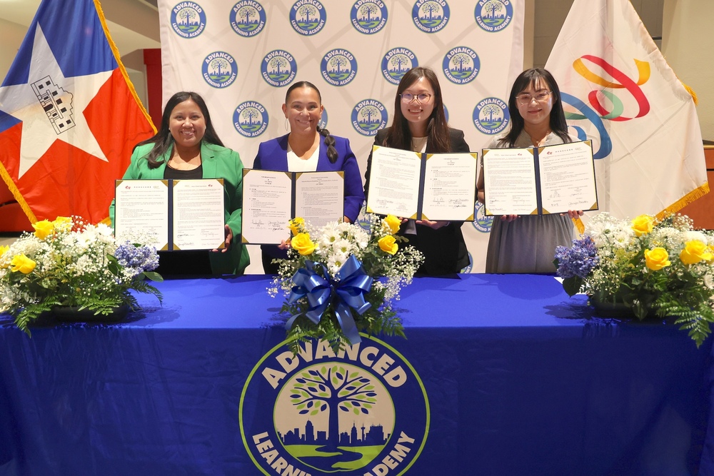 Four females holding signed agreements