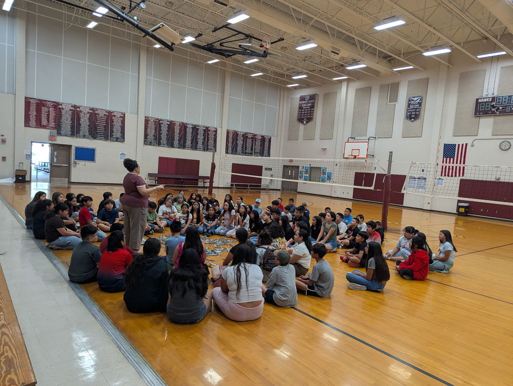 kids sitting in a circle in the gym.