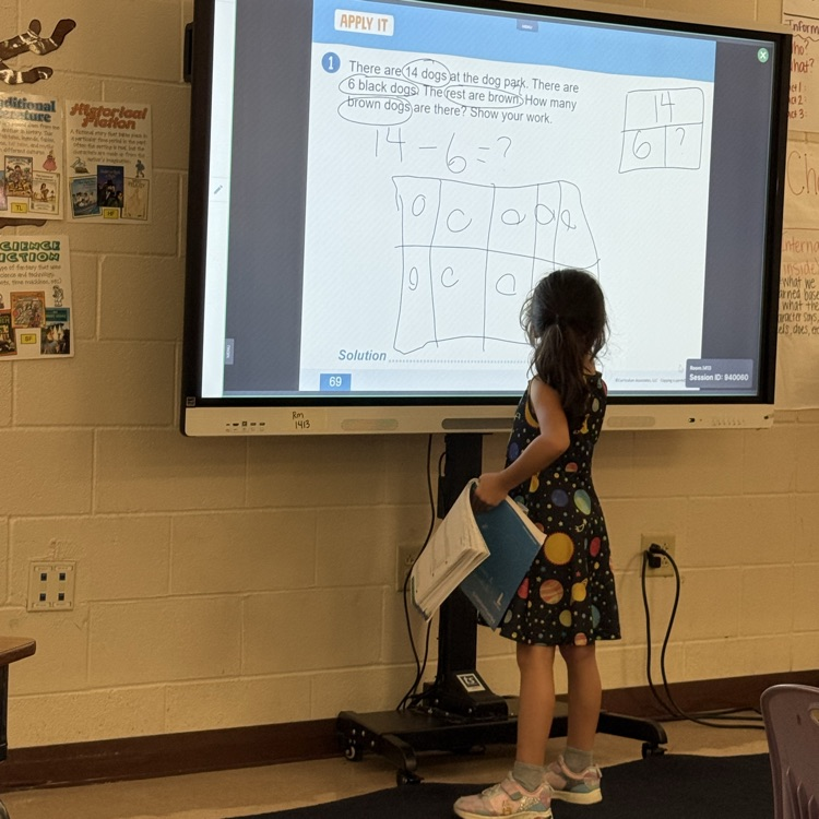 A student models the strategy on the board for the class.