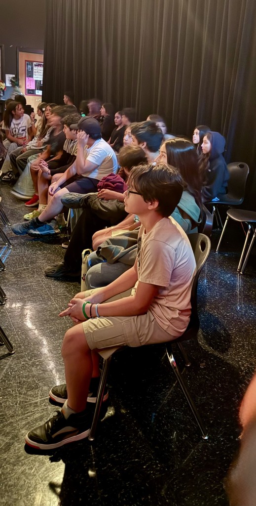 Students watching performance, black curtain in back