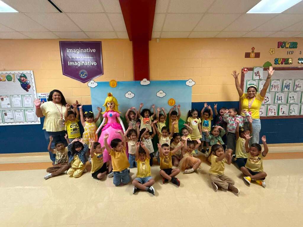 kids' classroom taking a group photo together wearing yellow with princess peach pinata