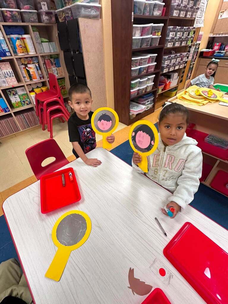 kids with paper cut outs of a face