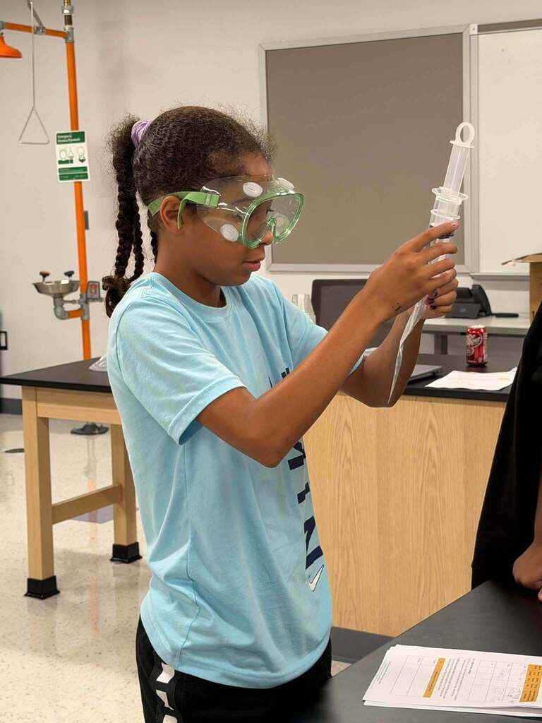 girl holding science equipment, doing an experiment