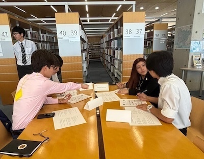 Four students at table in library in Japan