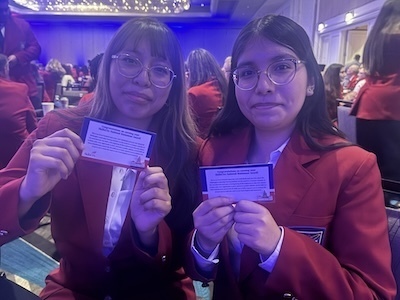 Two students holding award pins