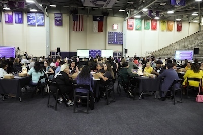 Group of people sit in Alamo Convocation Center at round tables