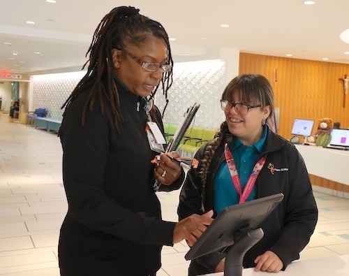 Intern helps teacher sign in at ipad