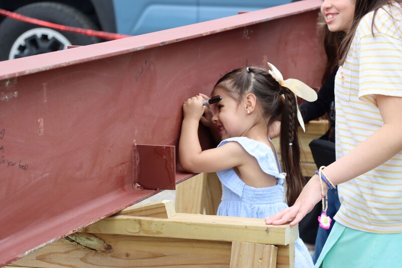 Student signs final beam at Highland Hills Elementary 