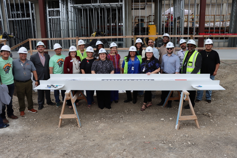 Fox Tech campus students and faculty stand behind final beam