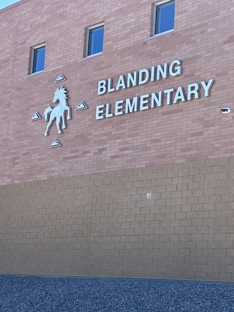 Red brick building with "Blanding Elementary" written above three windows. A white horse logo is above the middle window.