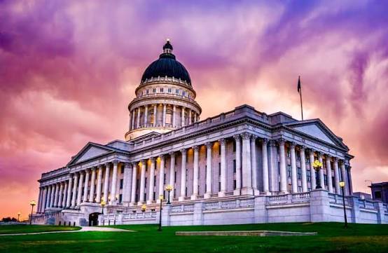 This is the Utah State Capitol with columns, green lawn, and a sunset sky.