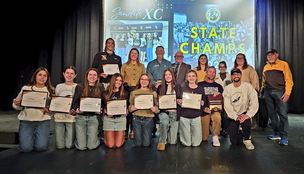 Sand Springs cross country athletes and coaches pose on stage holding certificates during the January 2026 Sand Springs Board of Education Meeting