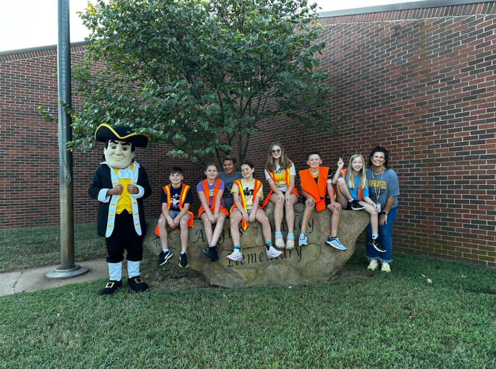 Students and staff from Angus Valley Elementary sit atop the Angus Valley Rock along with the Sandites mascot.