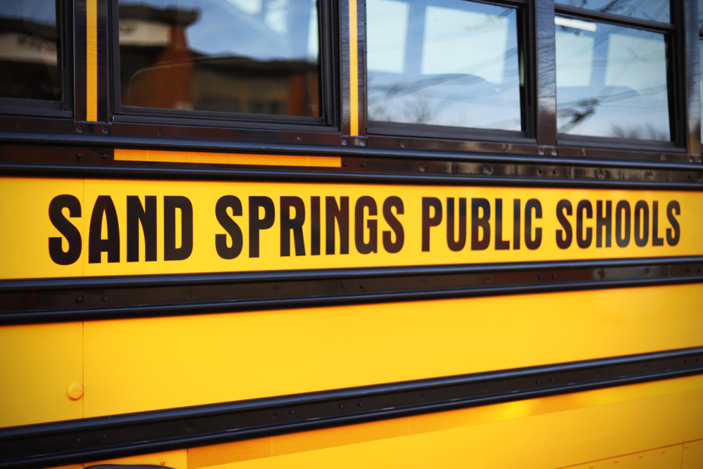 Side of yellow school bus that says Sand Springs Public Schools