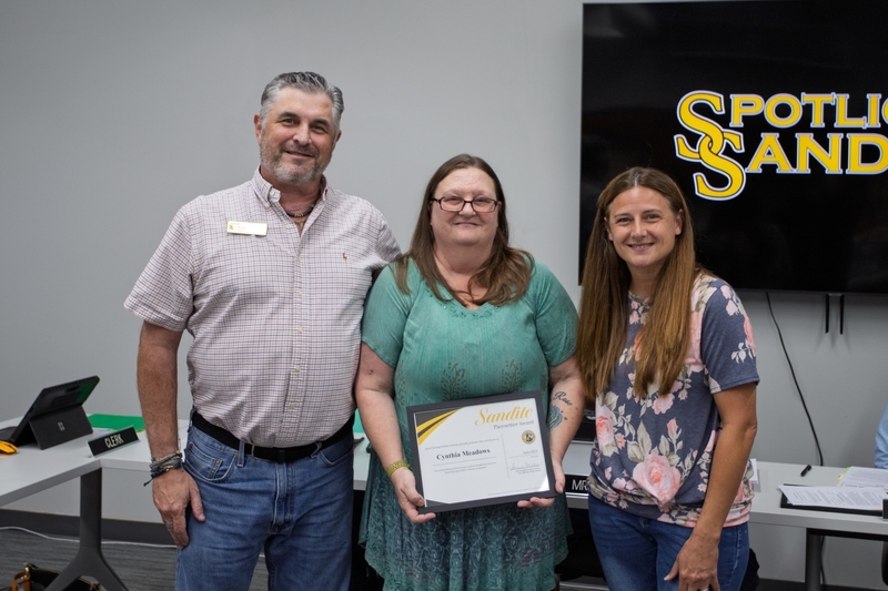 Cynthia Meadows stands with Erich Anderson and board member Alesha Spoon. Cynthia is holding a certificate for the Sandite Pacesetter Award