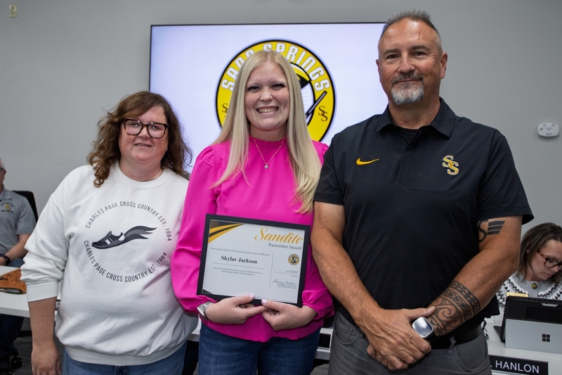 Skylar Jackson holding the Sandite Pacesetter Award, standing next to Board President Whitney Wagers and Athletic Director Rod Sitton