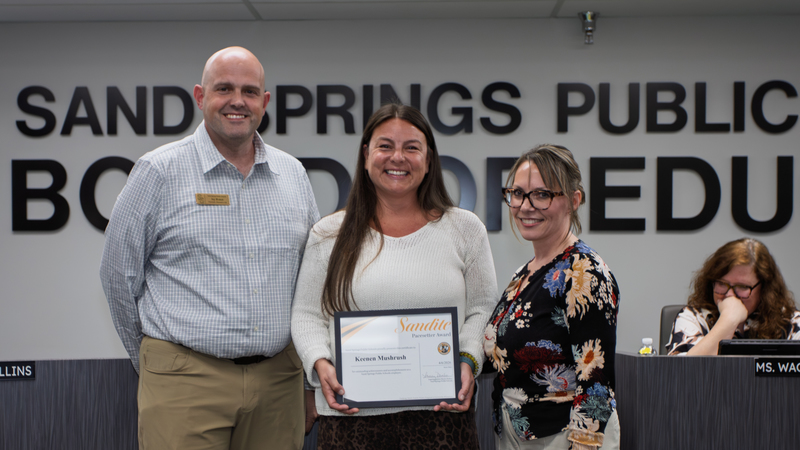Page Academy administrative assistant Keenen Mushrush receives certificate of recognition from board member and principal.