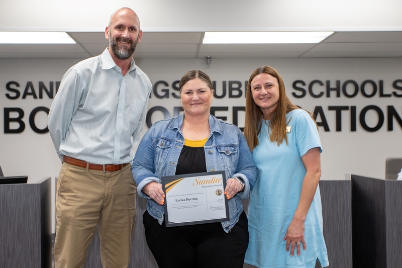 Erricka Herring receives certificate of recognition from school official and board member.