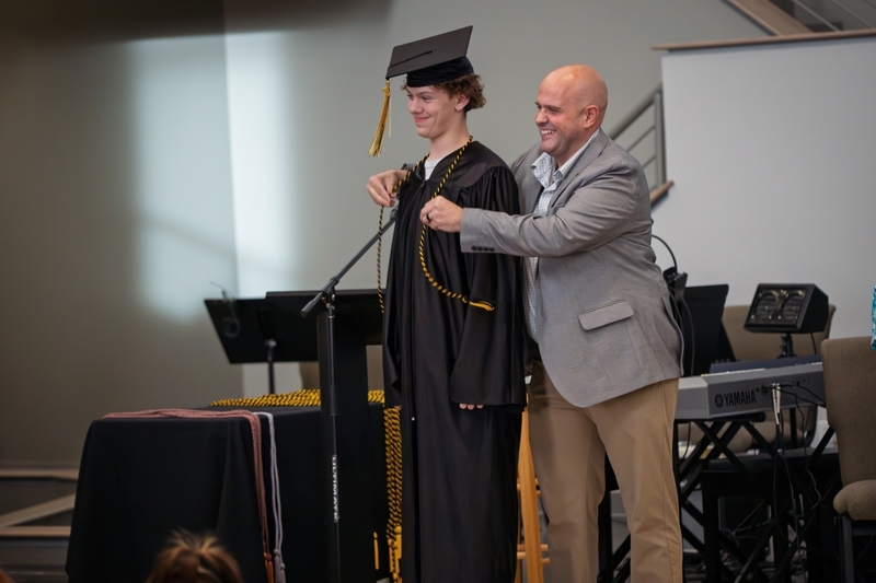 Page Academy principal Jay Rotert presents student with ceremonial cord.