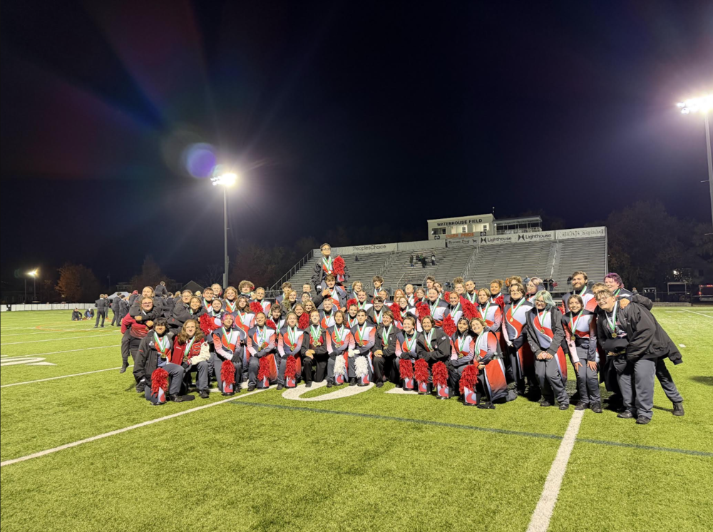 The SHS Marching Band poses for a photo on a football field.