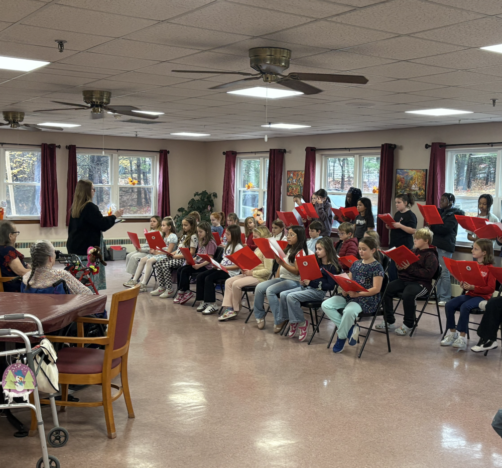 On Veterans Day, Sanford Pride's 4th grade chorus students traveled to Pinnacle Health in Sanford to honor local veterans with a special musical performance. What began as a simple visit turned into an unforgettable experience for both students and residents alike. The young singers delivered beautiful performances that filled the facility with joy, and each student had prepared handmade cards and letters to present to the veterans. While some children were initially shy about speaking with the residents, those hesitations quickly melted away as conversations began to flow naturally. By the time the bus arrived to take the students back to school, teachers found it nearly impossible to gather the group—the 4th graders were so engaged in their conversations with the veterans that they didn't want to leave! The feeling was clearly mutual, as several residents seemed delighted to welcome their "35 new grandchildren" for the afternoon. "It was a heartwarming, eye-opening, and positive experience for our students to have," said music teacher Meaghan Mannino. This intergenerational connection provided students with meaningful lessons that extended far beyond the music—about taking time to listen, connect, and show appreciation to those who have served our country.