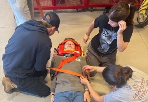 This is part of a series highlighting the career and technical education programs offered at Sanford Regional Technical Center. When someone calls 911, Emergency Medical Technicians are often the first medical professionals to arrive on scene. In Sanford Regional Technical Center's EMT Program, students learn the knowledge and skills needed to provide emergency medical care—from initial patient assessment through treatment and transport. The program is led by instructor Sharon Jackson, who has been in the EMS field since age 15 and a licensed provider for 25 years. A proboard certified Firefighter I & II and paramedic, Jackson still works as a firefighter/paramedic when not teaching, bringing current real-world experience into the classroom. The program currently holds the record for the highest number of students who have gone on to become licensed EMTs in its history. Students study anatomy, physiology, and pathophysiology while learning EMT assessment and treatment protocols for both medical and trauma patients. The hands-on curriculum includes patient assessments, vital signs monitoring, medication administration within the EMT scope of practice, and proper techniques for lifting and moving patients using various equipment types—all skills required of certified EMTs. "The EMT program at SRTC is a perfect opportunity for those who have an interest in emergency medicine to learn the skills, confidence, and procedures to help those in need with great support from the instructor and those around you. This class teaches you everything you need to pass your NREMT and work on an ambulance helping those in need and is a fun and engaging class along the way. I don't think I would want to spend my time in the mornings anywhere else” said Rowan Berounsky-Porter (currently an EMT and Marshwood student, Firefighting I & II program completer and SRTC Student of the Year Nominee).  The program provides seven college credits through Southern Maine Community College and American Heart Association CPR certification. Students also earn several specialized safety certifications that teach them how to handle hazardous materials incidents, report suspected abuse or neglect, and provide immediate bleeding control—skills that prepare them for the full range of situations EMTs encounter. Students describe the program's positive environment in their own words. Kelsey Chagnon, SRTC, York senior and Firefighting I & II program completer added, "It's a really positive environment and everyone is comfortable with each other." Jackson's teaching philosophy centers on meeting students where they are. "My students have taught me that they want to learn and not everyone learns the same way," Jackson said. "This means we must adjust the way we teach to meet the way they learn instead of trying to get them to adjust the way they learn to meet the way we teach." With a nationwide shortage of EMS providers, communities across the country need qualified EMTs to respond to emergencies. The program equips students with professional certifications, hands-on experience, and the clinical knowledge to begin their EMS careers or continue their education in paramedicine or other healthcare fields immediately after high school.