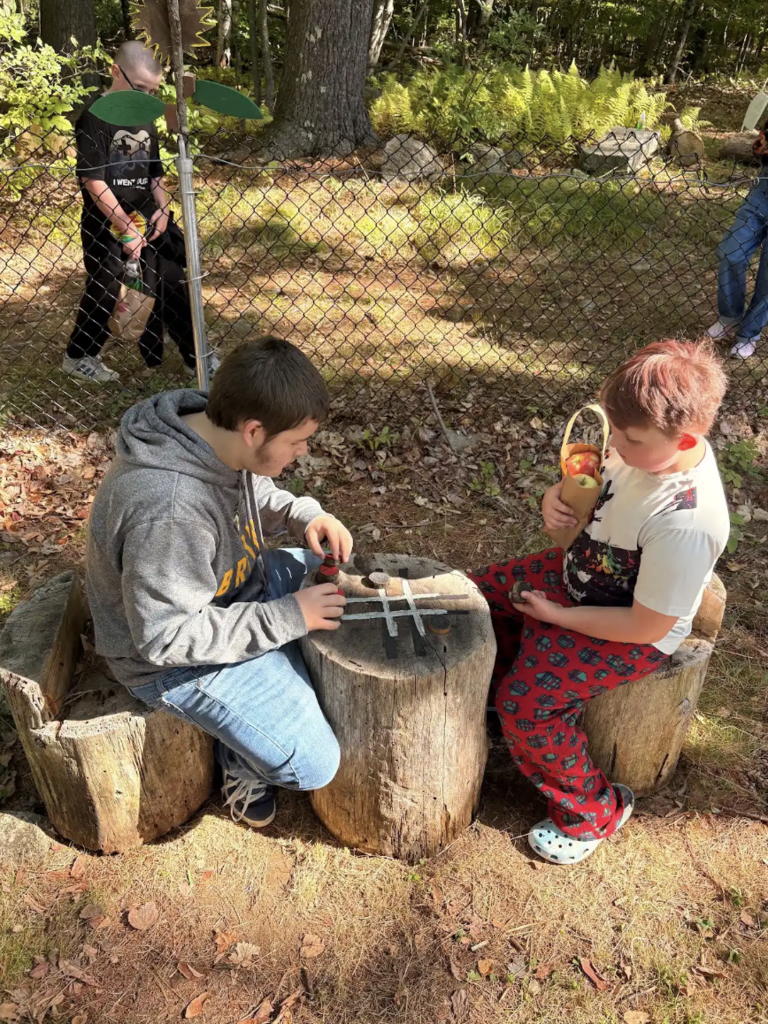 Two students play tik tak toe together on a log.
