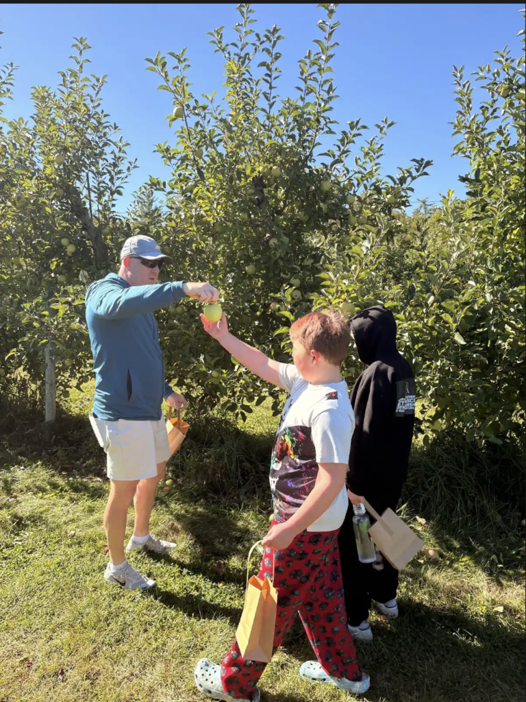 A staff member hands an apple to a student.