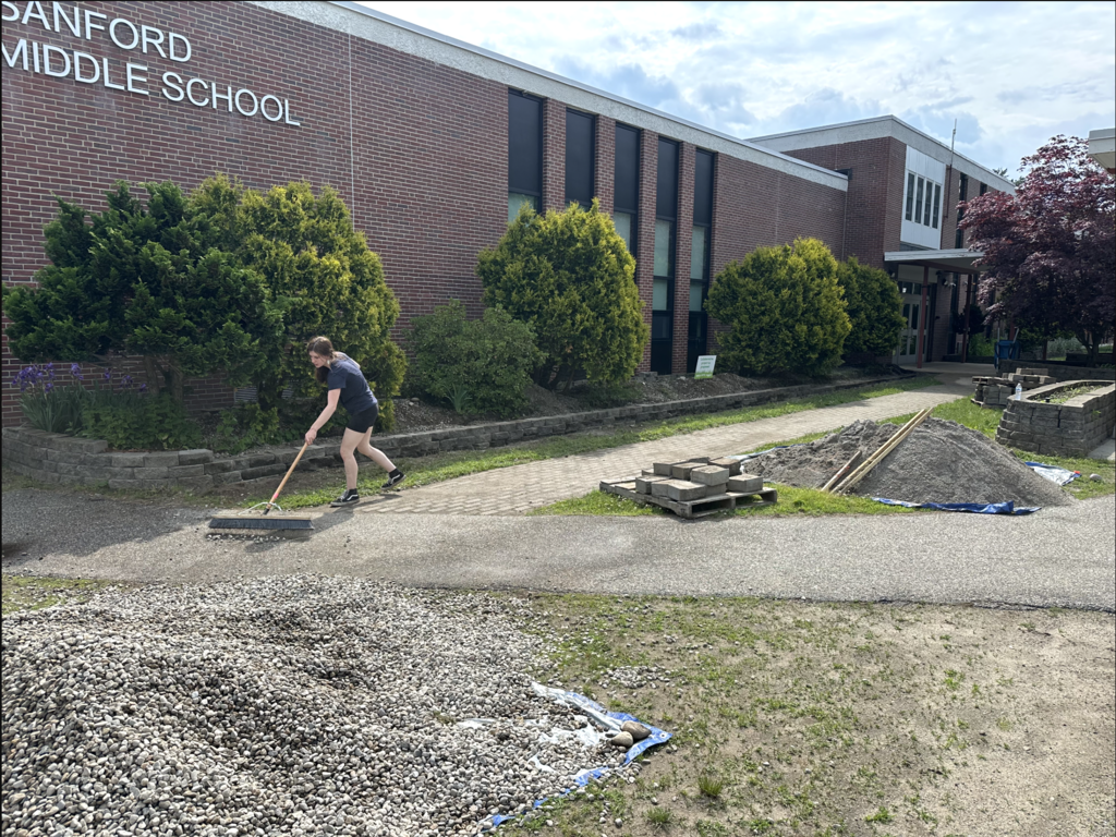 A student rakes outside the campus.