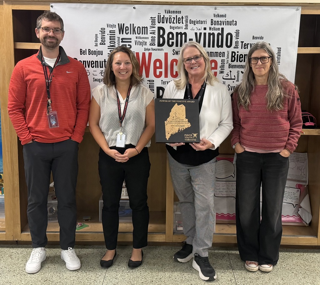 Four school counselors pose for a picture with an award from Maine Youth Thriving.