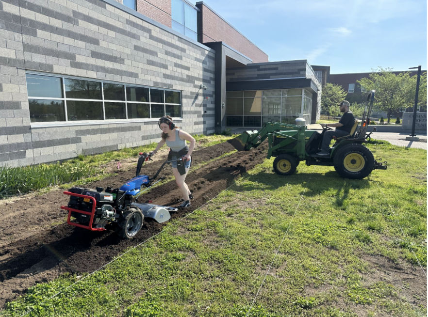 Two students operate equipment to till the dahlia field.