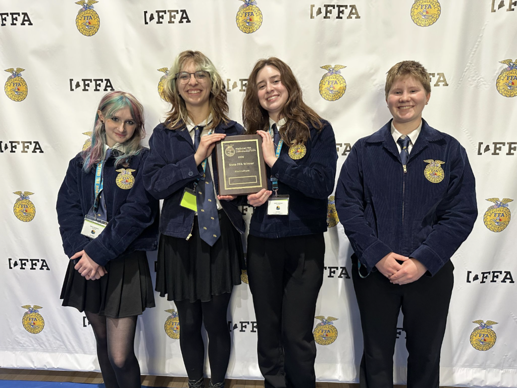 Four students stand presenting their award at the FFA State Convention in May.