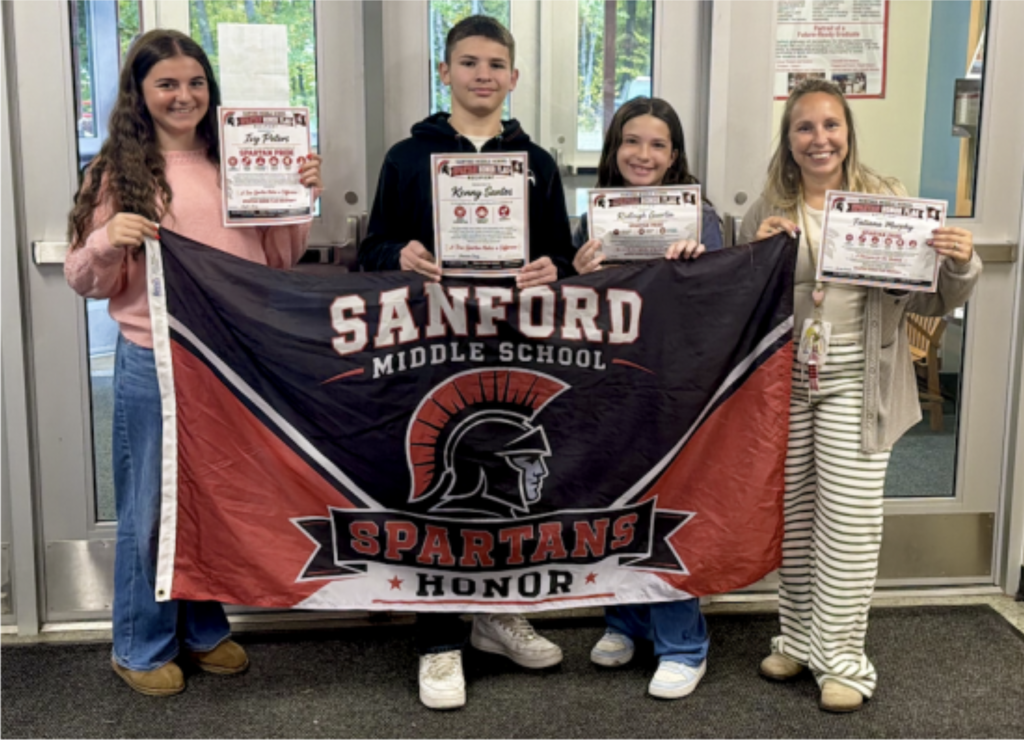 Three students and one teacher pose with the Spartan Honor Flag.
