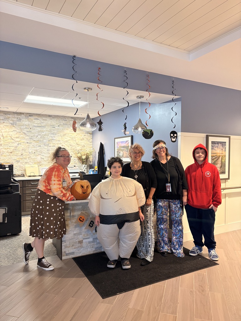 A staff woman at the nursing home poses with two students and two staff members.