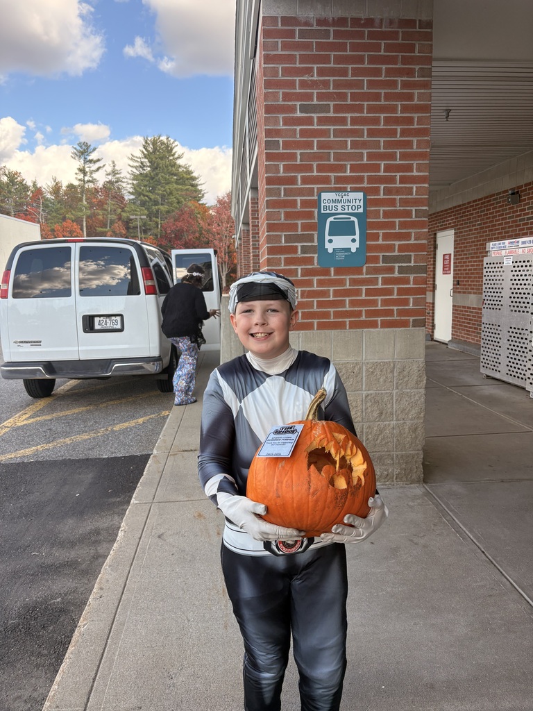 A student poses with a pumpkin.