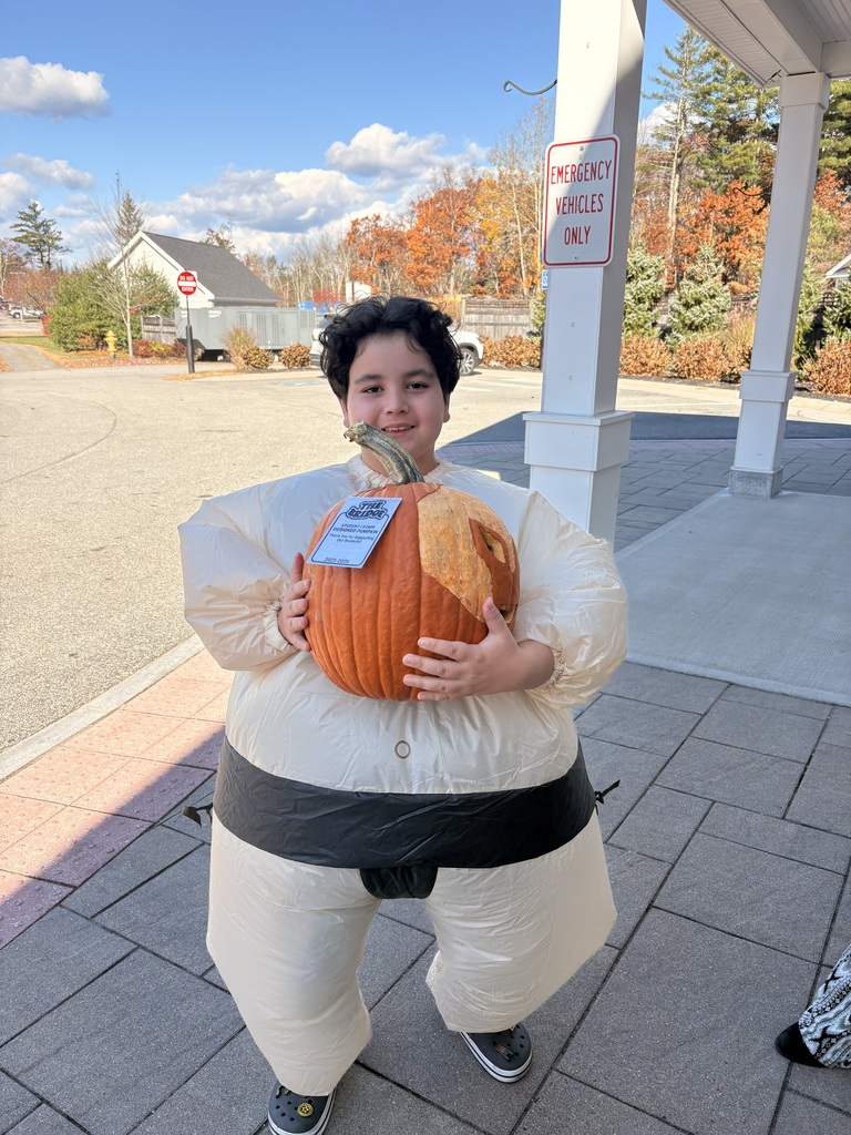 A student in costume holds a pumpkin for a photo.