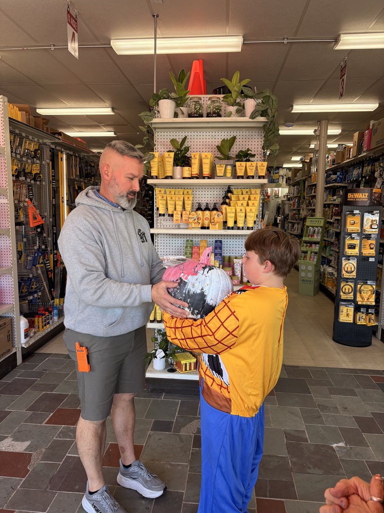 A student hands a pumpkin to a man.