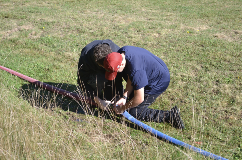 Two students collaborate on an activity with a fire hose.