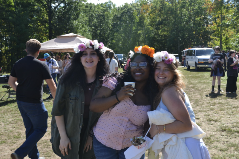 Three girls wearing flower crowns pose together.