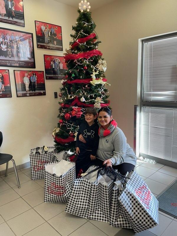 Mom and son with giftbags next to the Christmas tree