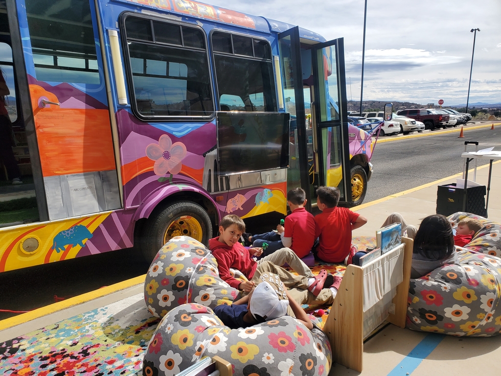 Kids doing an activity on side walk with mobile library in the back