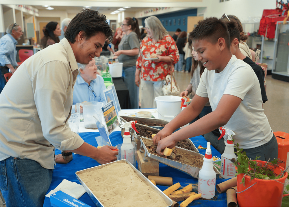 student digs in a pile of sand while learning about erosion from the Santa Fe Watershed Association.