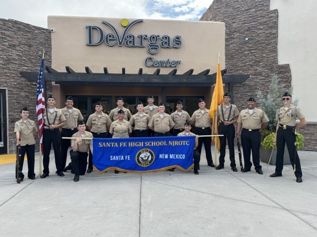 A group of uniformed individuals stand before a building with "Devargas Center" written above it.