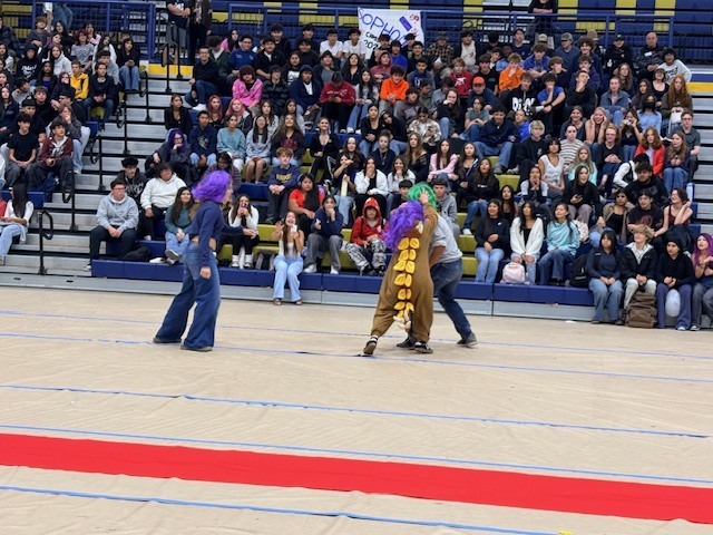 A group of people in costumes perform on a stage in front of an audience.
